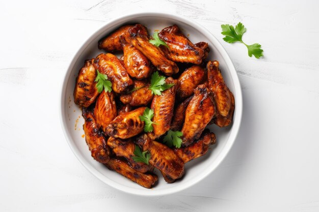 Chicken wings grilled in a bowl on a white table viewed from above