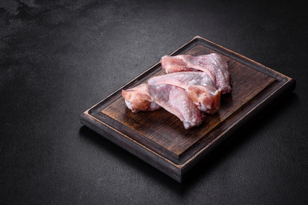 Chicken wings lie on a wooden board on a black background