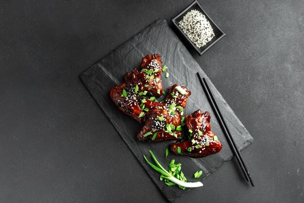 Chicken wings with sesame and green onions traditional asian recipe dark background top view