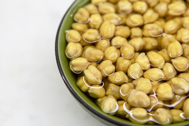 Chickpeas soaked in water in bowl on marble table concept of healthy eating veganism