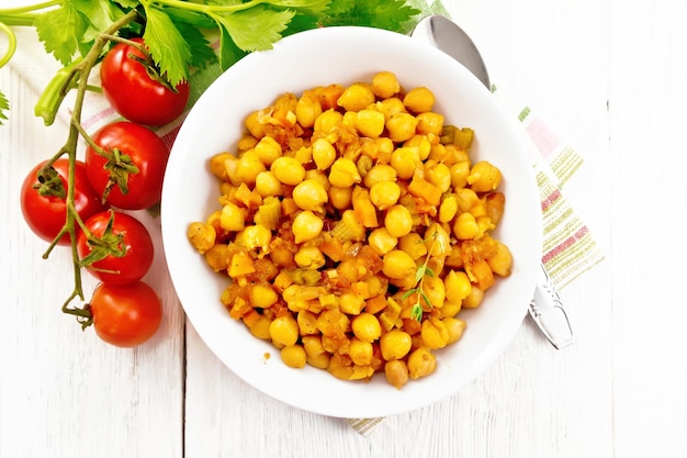 Chickpeas stewed with celery tomatoes onions carrots and garlic in a plate on a towel on wooden b