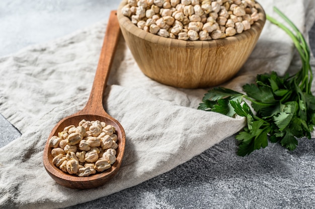 Chickpeas in a wooden spoon. Healthy vegetarian food. Gray background. Top view