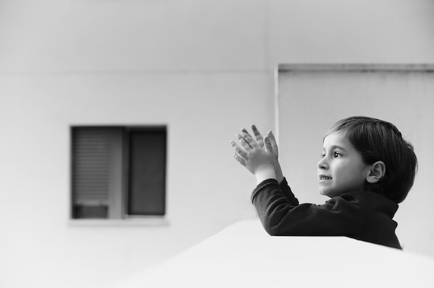 child applauding from the balcony of his house