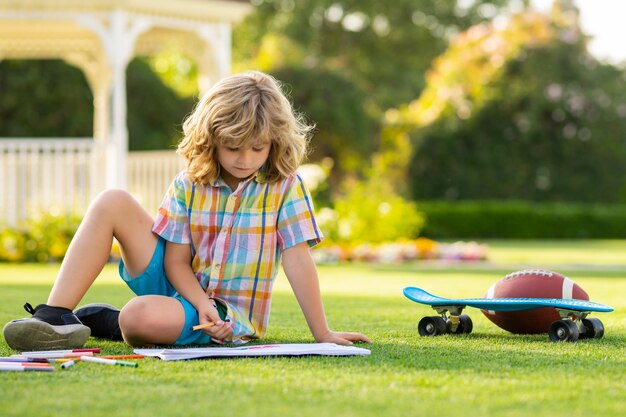 Child artist paints creativity vacation kid boy draws in park laying in grass having fun on nature b