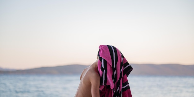 Child on the beach with a towel over her head