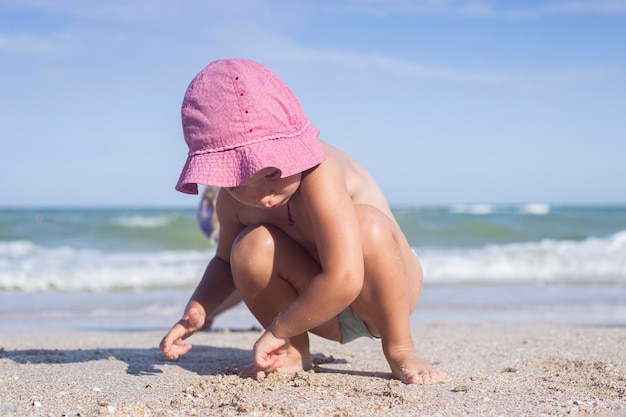 Child blond girl plays builds castles on the beach