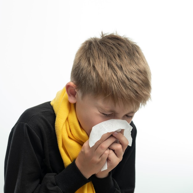 A child blows his nose into a napkin children's seasonal diseases a boy wrapped in a scarf