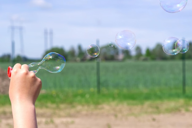 The child blows soap bubbles in nature