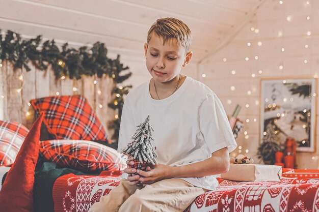 Child boy decorating Christmas tree at home Family with kids celebrate winter holidays Kids decorate living room and fireplace for Christmas