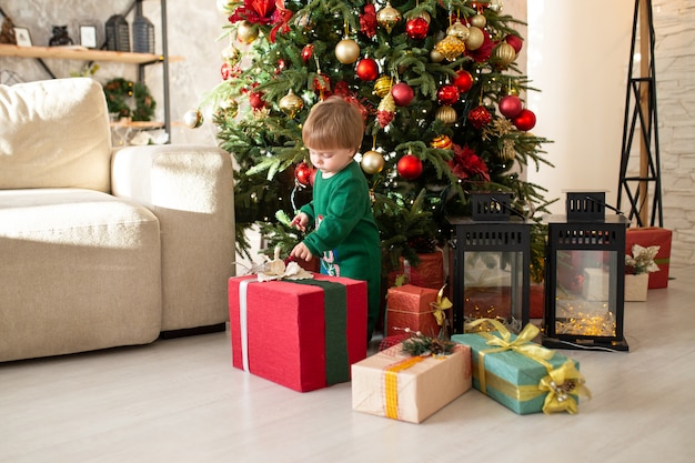 Child boy having fun with christmas tree.