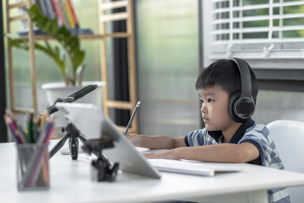 Child boy is using communicates on the Internet at home. homeschooling, distant learning, Asian little boy taking a class online and happy for Homeschool Quarantine.