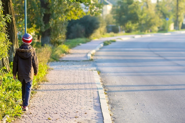 Child boy walking alone on a sidewalk