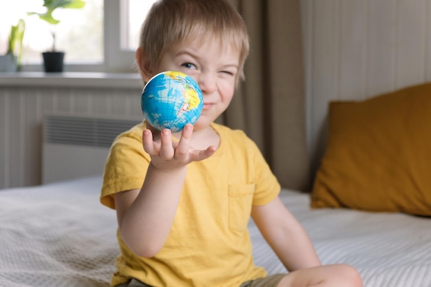 Child boy with blonde hair hugging earth globe save the earth 3 years old kid holding planet model