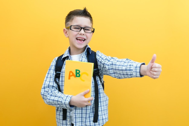 Child boy on a yellow wall background Great idea Happy smiling schoolboy goes back to school Success motivation winner genius concept