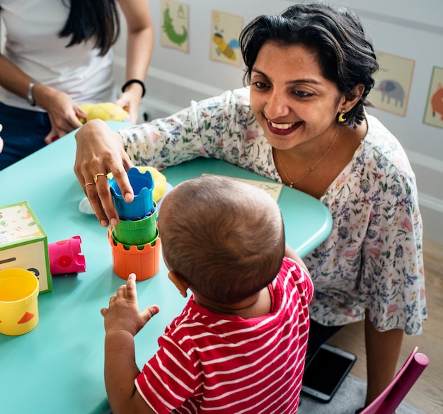 Child building blocks with a teacher in the nursery