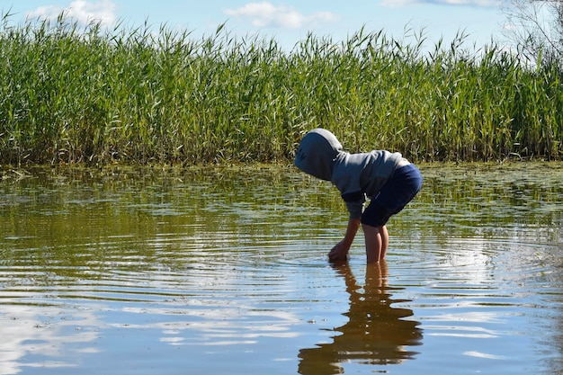 Child catches fish by hands. Cheerful childhood.