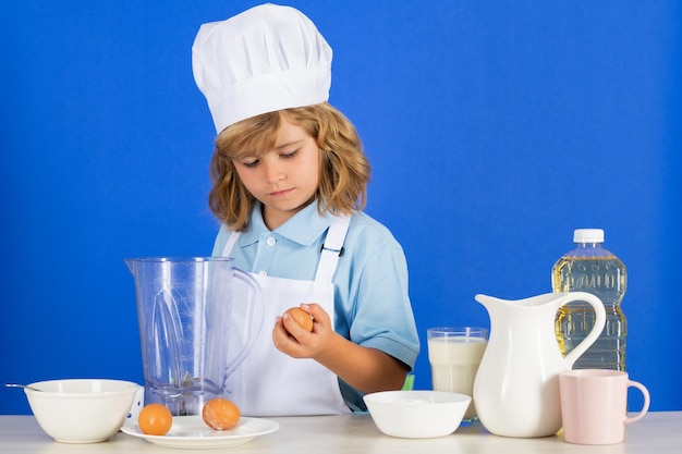 Child chef isolated on blue funny little kid chef cook wearing uniform cook cap and apron cooked foo