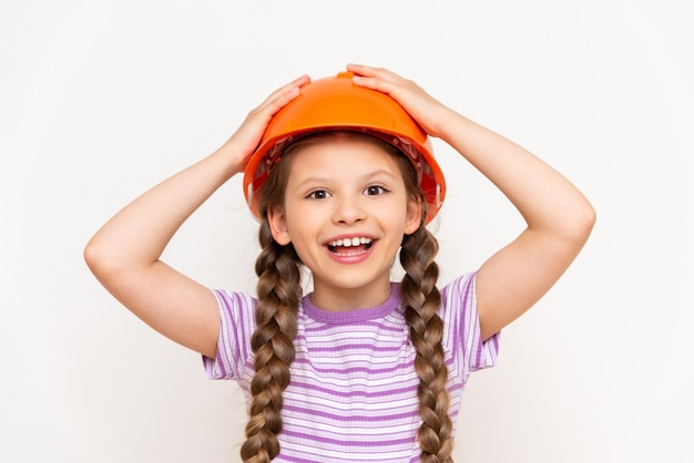 A child in a construction helmet holds his head with his hands A beautiful little girl is getting ready for repairs on a white isolated background