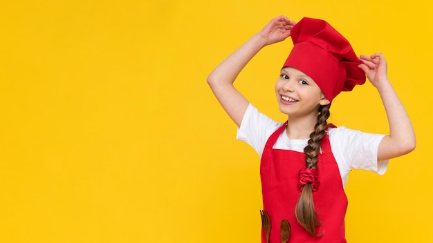 A child in a cook costume on an isolated background a little beautiful girl is going to cook food the concept of cooking by children