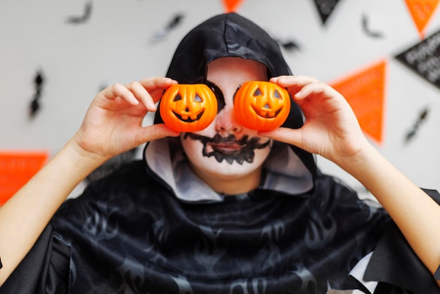 Photo child in costume holding halloween pumpkins