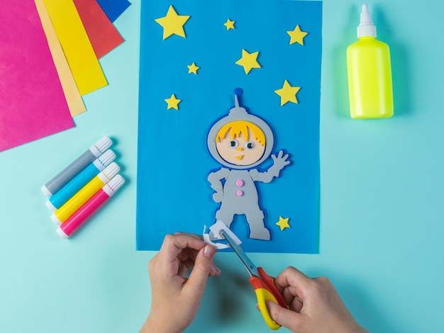 The child cuts out the paper astronaut and stars