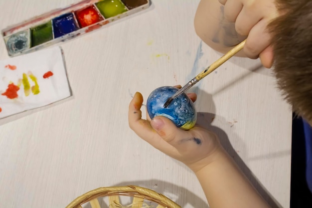 A child decorates an Easter egg with a tassel. The concept of religion, Easter.