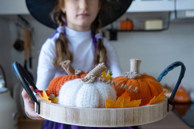 Child decorates the kitchen in home for Halloween Girl in a witch costume plays with the decor for the holiday bats jack lantern pumpkins Autumn comfort in house Scandistyle kitchen loft