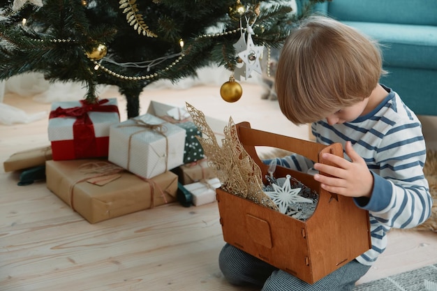 Child decorating a Christmas tree sitting in pajamas in a home interior