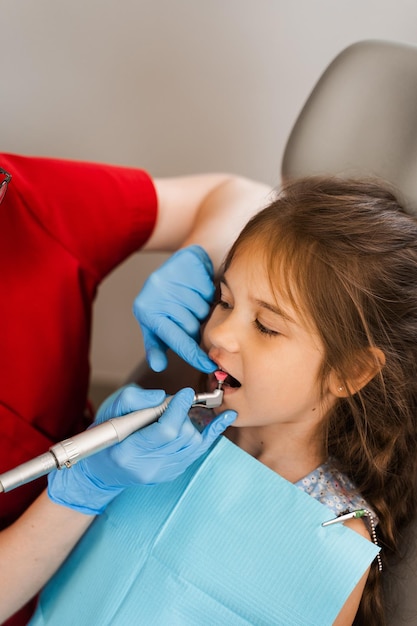 Child dentist makes professional teeth cleaning in dentistry Professional hygiene for teeth of child in dentistry Pediatric dentist examines and consults kid patient in dentistry