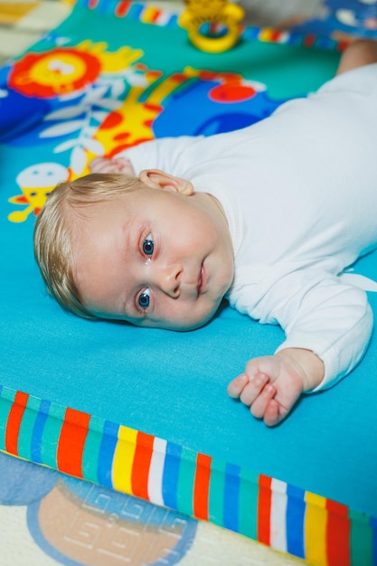 Child development The baby lies on the developing mat and plays with toys While playing the child gets to know the world and learns shapes and colors