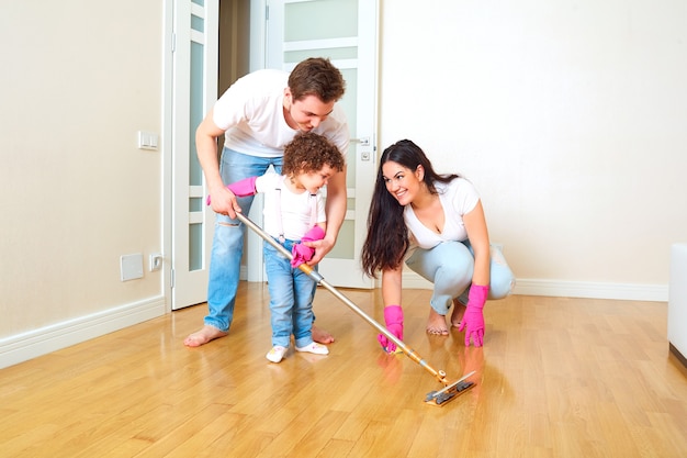 The child does wet cleaning with mom and dad children in the family kid cleans mop the floor in the room with parents the concept of family and education of children