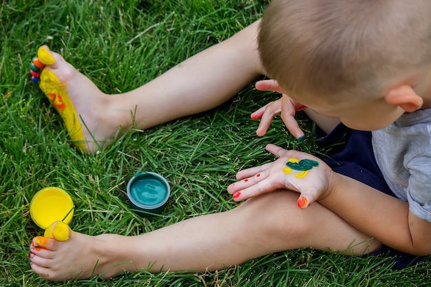 The child draws a pattern on the leg. A funny drawing with bright colors on the body. Selective focus