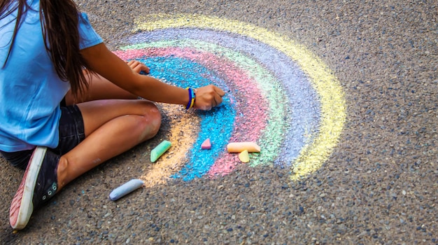 A child draws a rainbow on the asphalt Selective focus