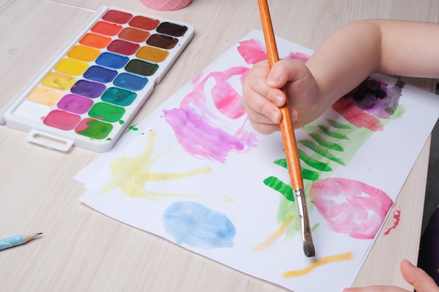 The child draws with a brush on paper