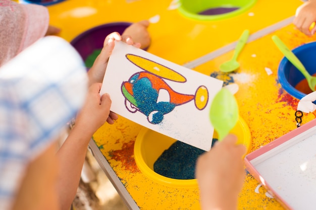 A child draws with colored sand picture. Cartoon characters.