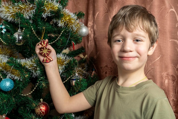 A child dresses up a Christmas tree with toys