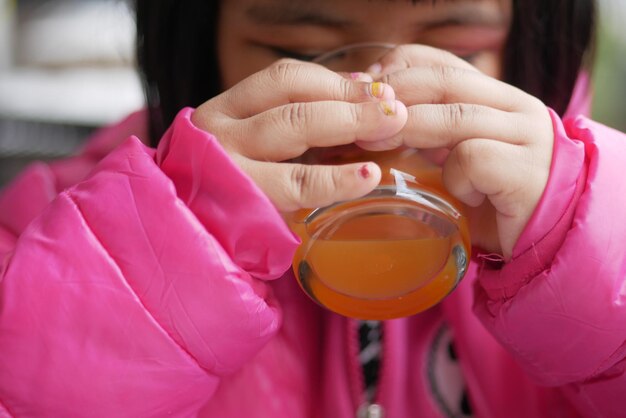 Child drinking glass of orange juice