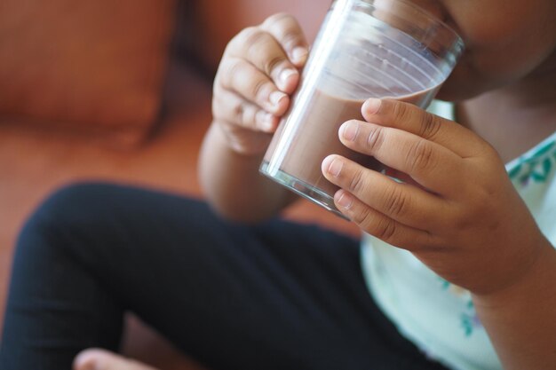 Child drinking tasty chocolate milk at home