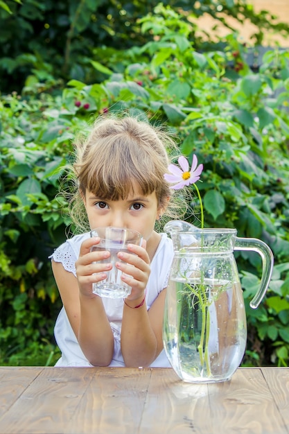 The child drinks clean water in summer. Selective focus.