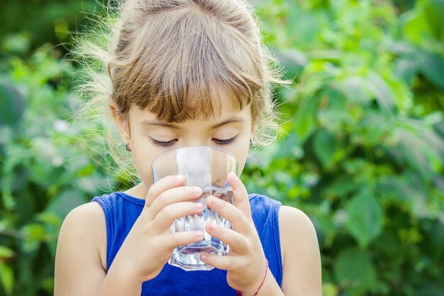 The child drinks clean water in summer. Selective focus.