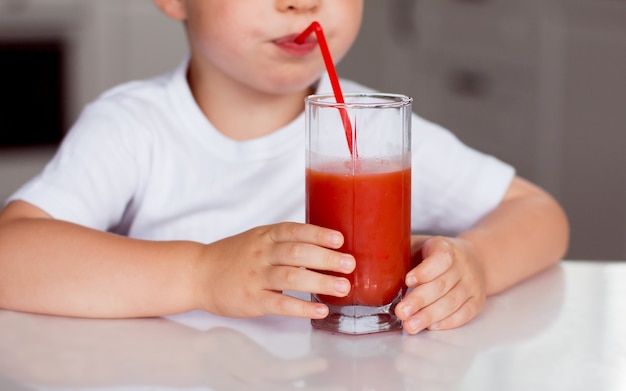 A child drinks red juice from a glass