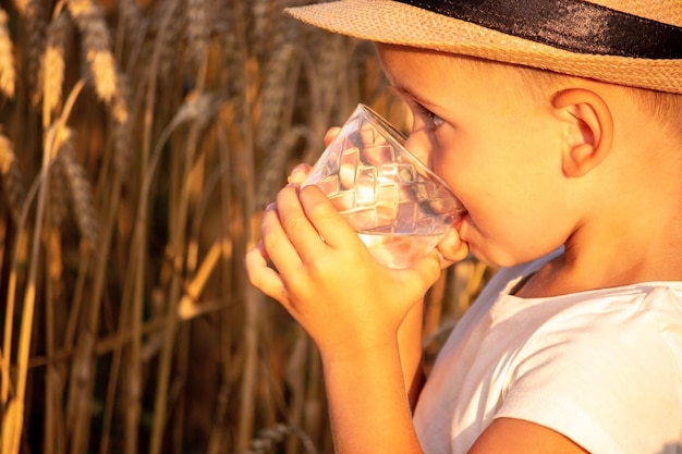 A child drinks water on the background of the field