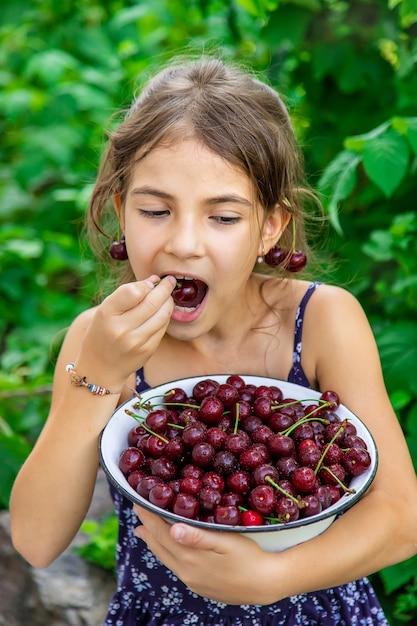 Child eats cherries in the garden background