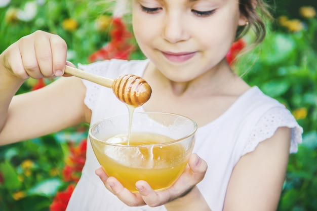 Photo the child eats honey. selective focus. nature.