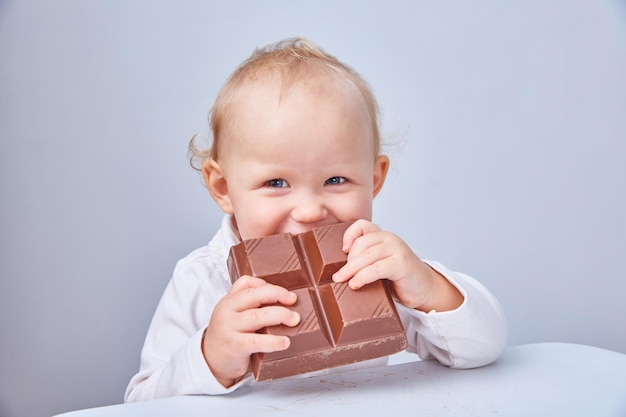 Child eats a large piece of chocolate. The concept of a junk food and healthy diet. Vegan chocolate.