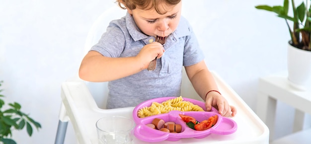 The child eats pasta and vegetables Selective focus