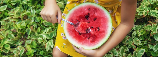 The child eats a watermelon with a spoon