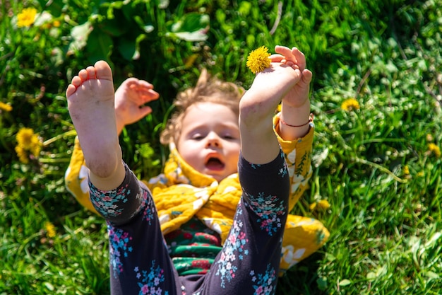 Child feet on the grass in the spring dandelions garden Selective focus