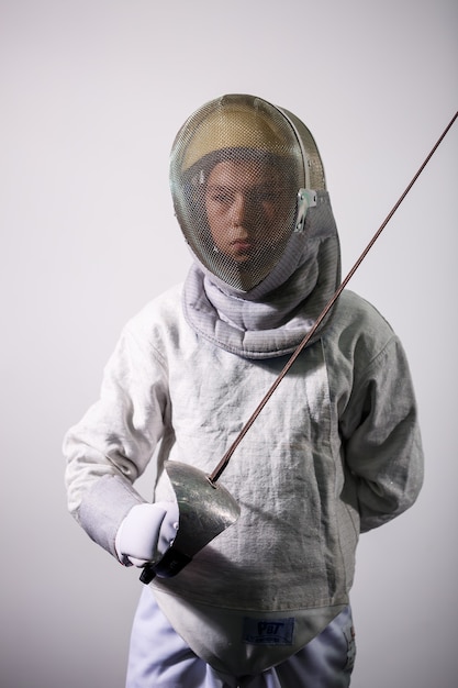 Photo child in a fencing suit with a sword in hand in the studio. young girls practice and practice fencing. sports, healthy lifestyle.