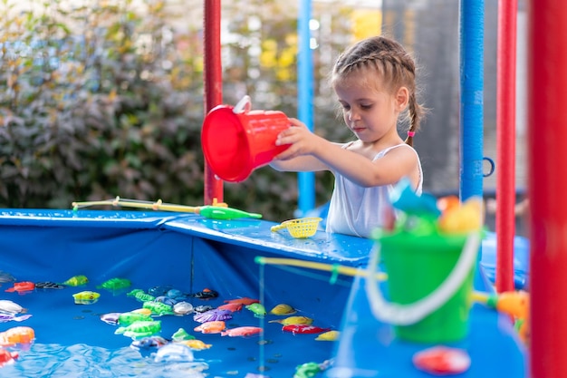 Child Fisher Catching Plastic Toy Fish On Pool Amusement Park